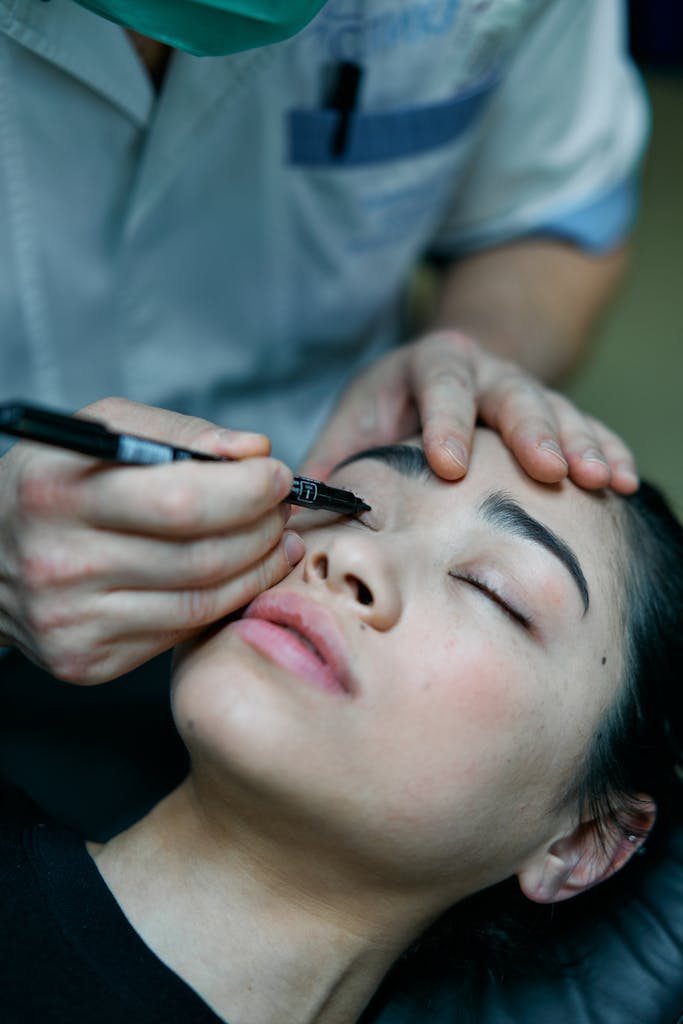 Cosmetologist marking eyelids for blepharoplasty on a patient.