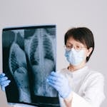 Medical professional in PPE examining chest X-ray results for diagnosis.